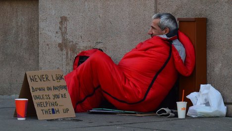 Obdachloser Mann mit Schild